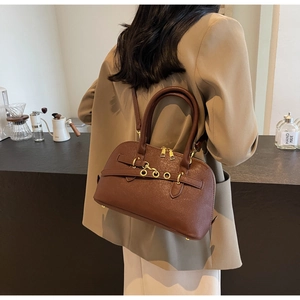 Detail of dark brown leather handbag featuring golden metal hardware and smooth texture