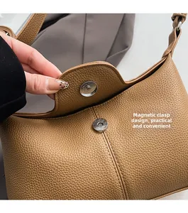 Detail of the magnetic buckle closure on a brown pebble leather shoulder bag
