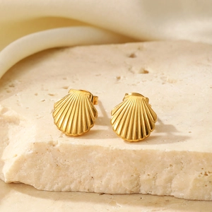 Detailed view of gold shell earrings with radiant texture on stone surface