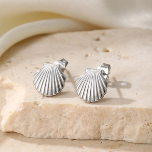 Elegant stainless steel sea shell stud earrings on natural stone background for women