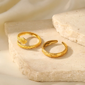 Detailed view of golden snake-shaped adjustable rings with intricate scale textures on stone