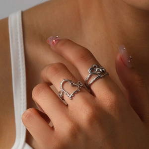 Close-up of vintage hollow heart stainless steel rings worn on fingers with polished finish