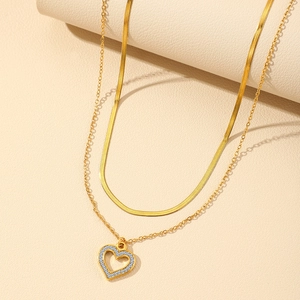 Close-up of layered 18K gold plated herringbone chain with zircon hollow heart pendant