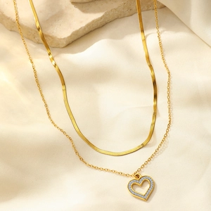 Detail of 18K gold plated double layer necklace with heart pendant on soft fabric