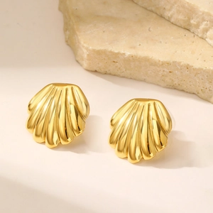 Close-up of golden shell-shaped earrings with textured stripes and metallic shine