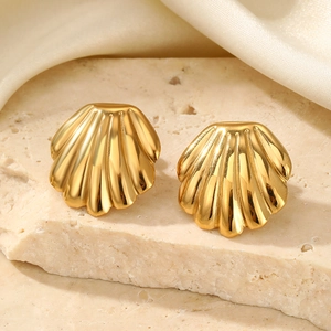 Detailed view of golden shell earrings featuring textured radial stripes on stone stand