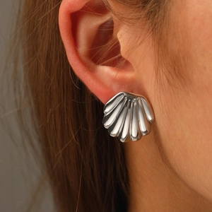 Close-up of polished silver shell-shaped earrings with fan-like textured pleats