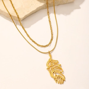 Détail du collier doré à deux rangs avec pendentif feuille ajouré sur support pierre