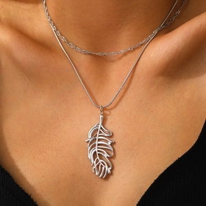 Détail d'un collier multicouche en acier inoxydable avec pendentif feuille et chaîne torsadée