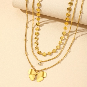 Détail d'un collier triple épaisseur doré avec disques gaufrés et pendentif noeud