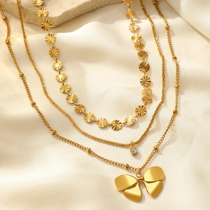 Détail du collier triple rang doré avec disque gaufré, strass et pendentif de papillon