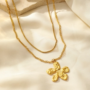 Close-up of golden double-layer necklace featuring a textured 5-petal flower pendant