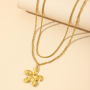 Close-up of double-layer gold necklace featuring a textured 5-petal lava flower pendant