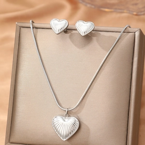 Silver heart pendant necklace and earrings set with radial texture on silk background