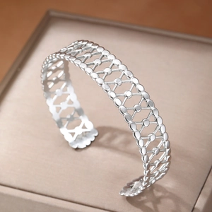 Polished silver geometric hollow cuff bracelet with X pattern shown in a gift box