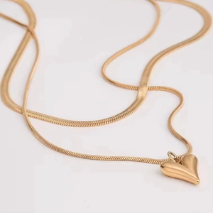 Macro detail of gold layered snake chain necklace with a polished heart pendant charm