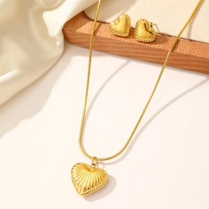 Détail de parure bijoux coeur doré avec texture en relief radial sur collier et boucles