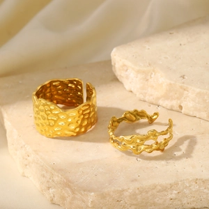 Detailed macro view of two-piece gold rings with lava texture on natural stone base
