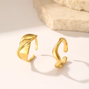 Macro detail of wave-shaped golden rings with matte finish on minimalist background