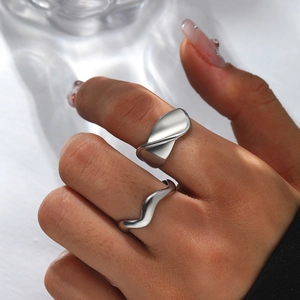 Close-up of minimalist wave-shaped silver rings set worn on fingers for modern style