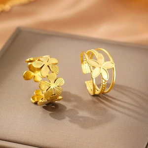 Detail of two gold floral open rings with intricate petals on a textured jewelry box