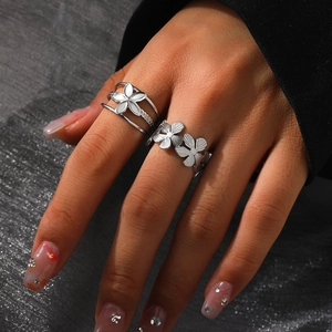 Two-piece silver stainless steel flower rings set for women on a dark fabric background