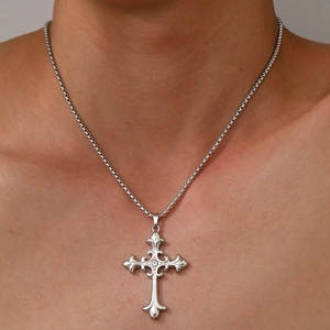 Détail d'un pendentif croix gothique en argent avec cristal porté sur le cou d'un modèle
