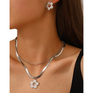 Detail of silver five-petal flower necklace and earrings set on model neck