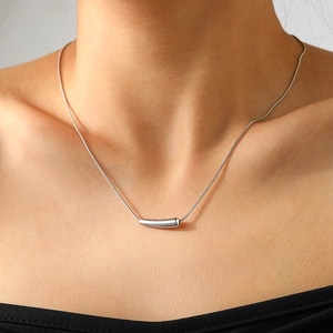Gros plan d'un collier en acier inoxydable avec pendentif barre courbée argentée et chaîne fine