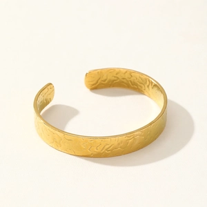 Detailed view of wide open cuff bangle with hammered gold texture and wrinkled metal surface