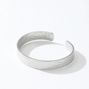 Detailed view of wide open cuff bracelet featuring irregular hammered silver texture