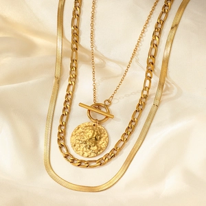 Macro view of triple-layer gold chains featuring coin pendant and T-bar toggle clasp