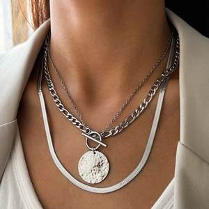 Close-up of triple-layered silver Cuban and snake chain necklace with hammered round pendant