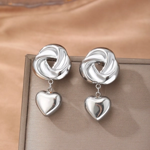 Polished silver stainless steel spiral knot earrings with heart pendants on satin