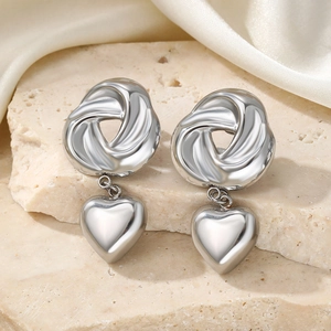 Silver spiral heart drop earrings on stone base with satin background display
