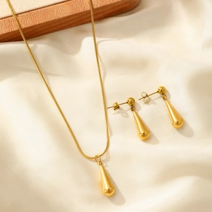 Detail of gold teardrop necklace and earrings set on an elegant silk background