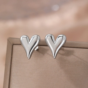 Polished silver heart stud earrings displayed on a premium textured jewelry box