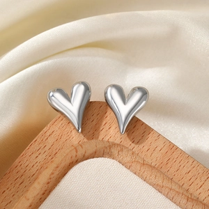 Detailed view of silver heart stud earrings displayed on a wooden jewelry stand