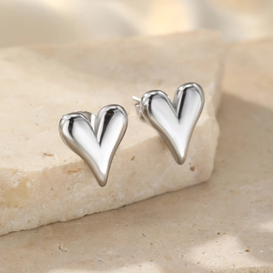Textured heart-shaped metal stud earrings displayed on a natural stone base