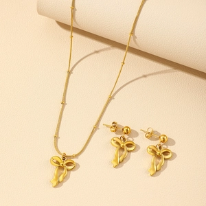 Détail d'un ensemble de bijoux avec collier à nœud et boucles d'oreilles plaqué or 18k
