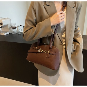 Detail of dark brown leather crossbody bag with gold buckle straps and metal feet