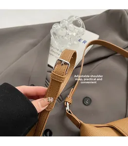 Detail of brown litchi pattern leather bag with adjustable silver buckle strap
