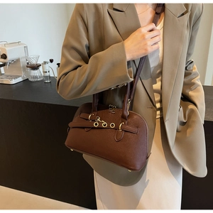 Close-up of a dark brown crescent bag featuring vintage matte leather and gold buckle details