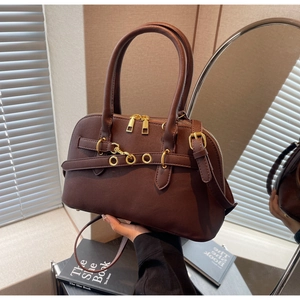 Detailed view of dark brown faux leather handbag with shiny gold hardware and dual zippers