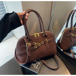 Detail of dark brown leather handbag with gold zippers, belt buckles, and dual handles