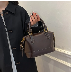 Detailed view of dark brown oil-wax leather texture and white stitching on Boston bag