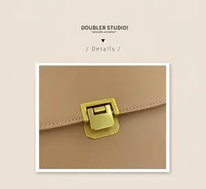 Close-up of golden metal clasp on a khaki leather crossbody bag with neat stitching