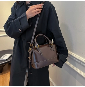 Detail of dark brown oil wax leather Boston bag with white stitching and gold hardware