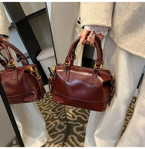Detail of dark reddish-brown oil wax leather Boston bag with white contrast stitching