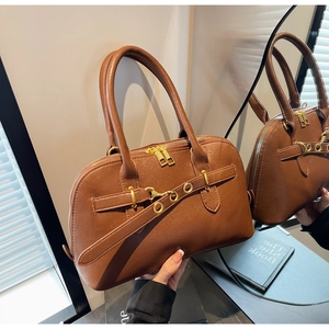 Detailed view of caramel leather handbag with vintage doctor bag style and gold hardware